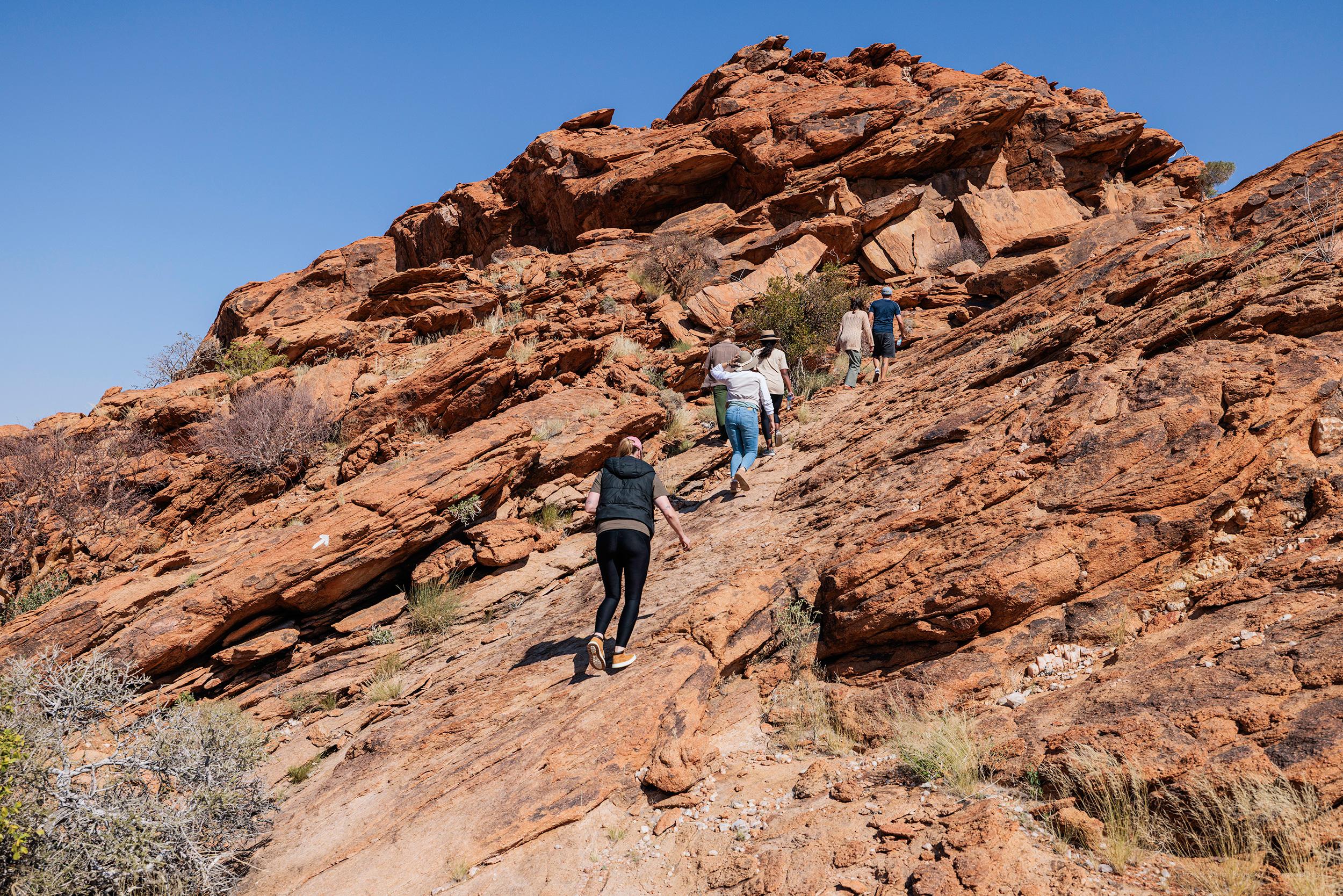 Hiker on a marked trail through dramatic Namibian desert canyon landscape with red rock formations
