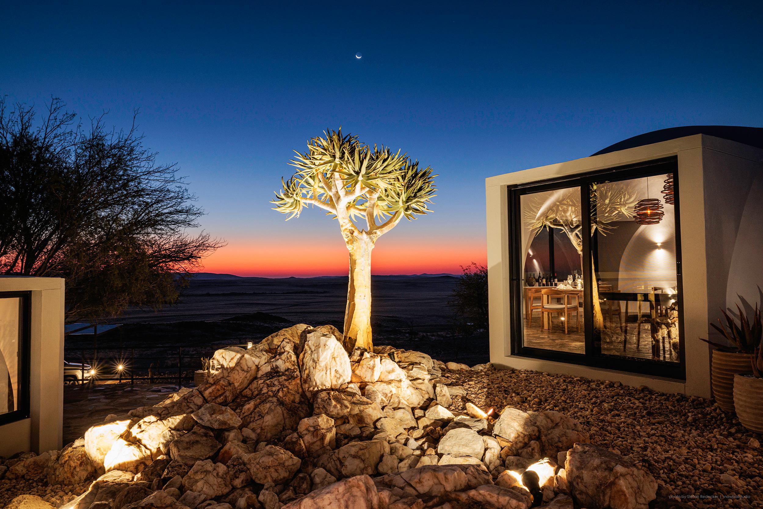 Private terrace of desert chalet with lounge chairs overlooking waterhole and desert plains